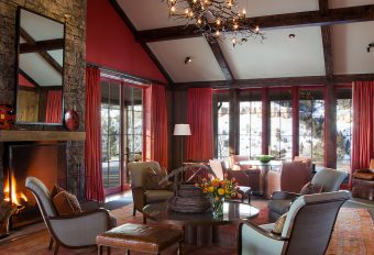 Drawing Room Western Lodge, red walls, red curtains, iron branch chandelier, comfortable upholstery, fireplace, timber frame ceiling
